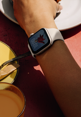 A person's arm grabbing a breakfast food, Apple Watch SE 3 on wrist, Starlight aluminum case, always-on display, portrait of a person on watch face, starlight Sport Band