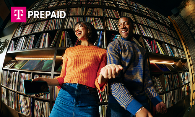 Two people dancing in front of shelves filled with vinyl records.